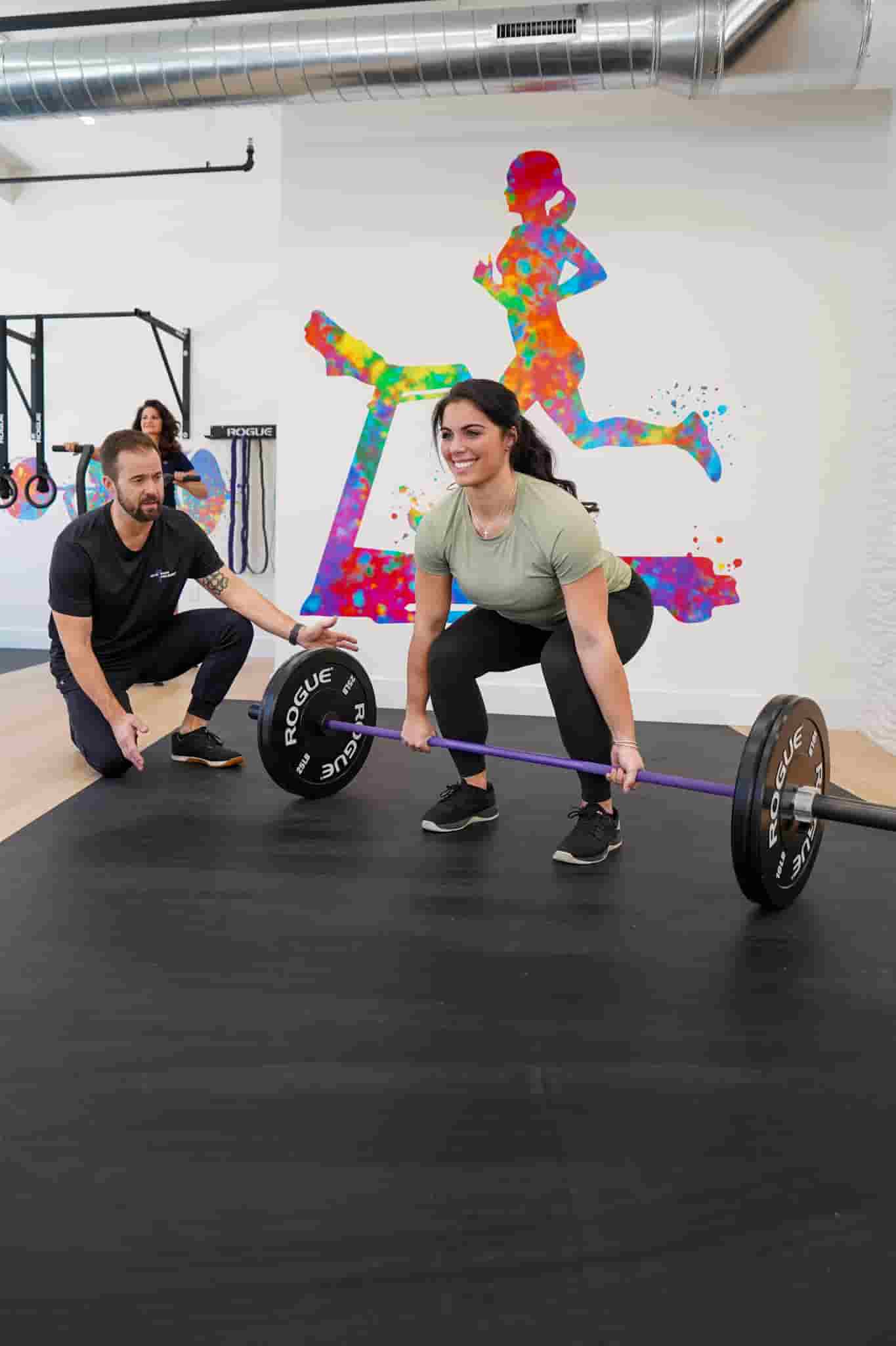 Woman lifting with trainer in gym